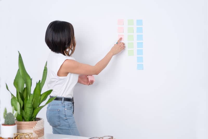 A woman pointing at sticky notes on a wall during a workshop